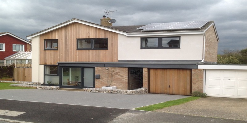 Exterior of a renovated home in Basildon, Essex, featuring freshly painted walls, stained wooden panelling, and a stained garage door, showcasing a clean and cohesive design.