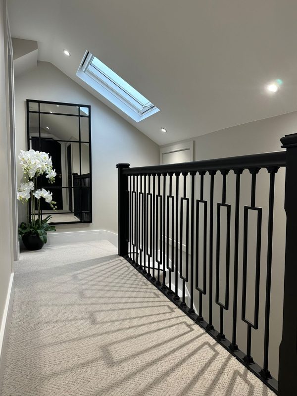 A hallway in Basildon, Essex, with freshly painted walls and ceiling, and a black handrail and balustrades adding a modern contrast to the space.